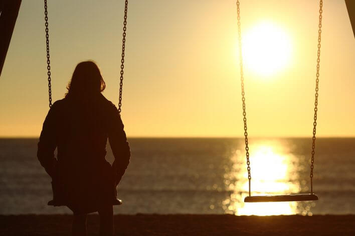 woman sitting on the swing at sunset