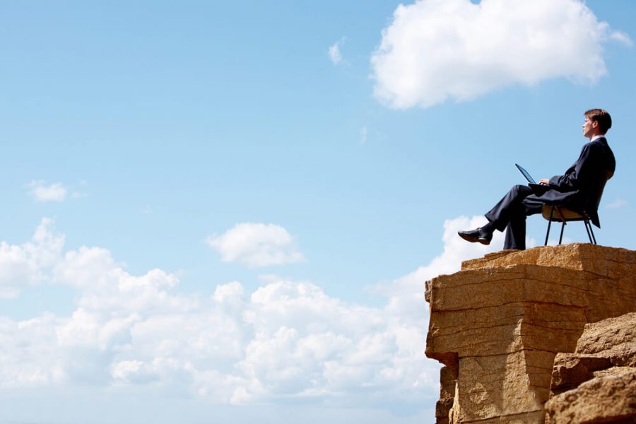 businessman sitting on the chair on edge of cliff