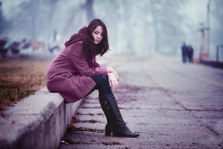 sad girl sitting on the sidewalk