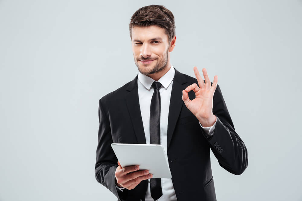 man with tablet winking and showing ok sign